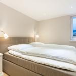 Bedroom with bed, nightstand, and sea view through window.