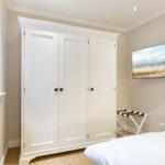 Bedroom with white wardrobe, bed, and wall picture