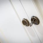 Key in the lock of a white door with metallic handles.