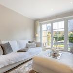 Living room with white sofa, ottoman, and view of the garden.