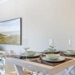 Dining table with four place settings, wall art, and sideboard in dining room.