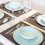 Table set with plates, bowls, and glasses on placemats.