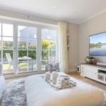 Living room with TV, sofa, and view of garden.