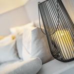 Schwarzer Drahtleuchter mit Kerze auf weißem Tisch neben Sofa