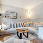 Wohnzimmer mit Ecksofa, Fernseher und Holztisch auf Teppich.