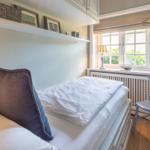 Schlafzimmer mit Bett, Stuhl und Fenster mit Blick auf Grün.