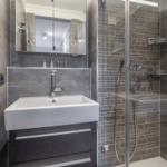 Bad mit Dusche, Waschbecken und Spiegelschrank.