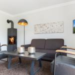 Wohnzimmer mit Sofa, zwei Sesseln, Kamin und Fernseher an der Wand.