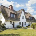 Wohnhaus mit Strohdach, weißen Wänden und Garten