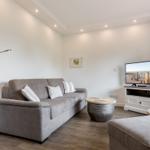 Wohnzimmer mit Sofa, Fernseher und Stehlampe.