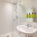 Bathroom with shower, sink, and mirror cabinet with bottles.