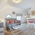 Living and dining area with sofa, table and chairs. Wooden floor and white walls.