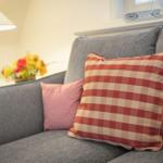 A gray sofa with checkered red-and-white cushions and pink.