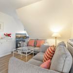 Living room with sofa, coffee table, and TV under sloped ceiling.