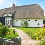 House with thatched roof, garden path, and flower beds.