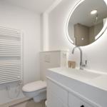 Badezimmer mit Waschtisch, Spiegel und Toilette.