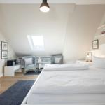 Schlafzimmer mit Dachschrägen, Bett, Sitzgelegenheit und Bücherregal.