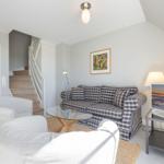 Wohnzimmer mit Sofa, Sessel, Glas-Tisch und Fernseher