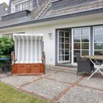 Terrace with beach chair, table and chairs in front of a house with sliding doors.