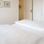 Bedroom with white bed, closet, and pictures on the wall.