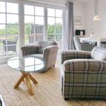 Living room with two patterned armchairs, glass table, and view of terrace.