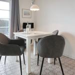 Dining room with white table, four gray chairs, and window to terrace.