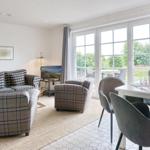 Living and dining area with plaid sofa, dining table, and garden view.