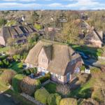 Traditional thatched house with garden and surrounding homes