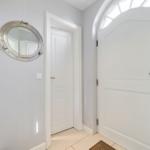 Entrance area with white door, round mirror, and tiled floor.