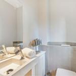 Bathroom with sink, mirror, and toilet. Decorative piece beside the sink.