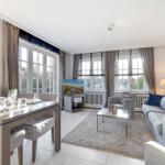 Living and dining area with sofa, table, and windows.