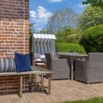 Terrace with seating and beach chair. Background: greenery and blue sky.