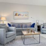 Living room with gray sofa, two armchairs, and glass coffee table.