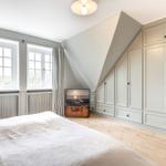 Schlafzimmer mit Dachschräge, großem Kleiderschrank und Fenstern mit Vorhängen.