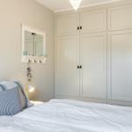 Schlafzimmer mit Bett, Kleiderschrank und Spiegel an der Wand.