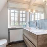 Badezimmer mit Waschbecken, Spiegel und Fenster