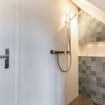 Dusche mit Duschbrause und grauen Fliesen an der Wand