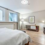 Schlafzimmer mit Bett, Sessel und Fenstern.
