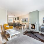 Wohnbereich mit Kamin, Essbereich und Küche im Hintergrund.
