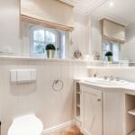Bathroom with sink, toilet, and window. White fixtures with mirror.