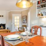 Dining room with table, chairs, and fireplace. Kitchen with white cabinets.