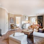 Living room with fireplace, sofa, and dining table in background.