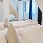 Bedroom with two beds, mirrored wardrobe, and window with curtains.