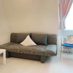 A room with sofa, table, chair and window with curtains.