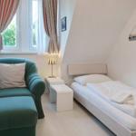 Bedroom with bed, green armchair, and window with curtains.