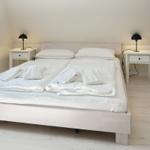Bedroom with white bed, two nightstands, and black lamps.