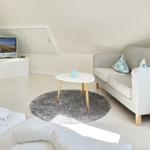 Living area with sofa, round rug, and TV under sloped ceiling.