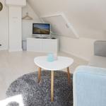 Living room with sofa, table, and TV under sloped ceiling