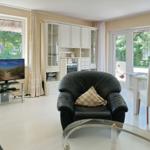 Living room with dining area, black leather armchair, and TV. View of garden.