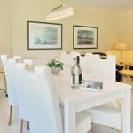 Dining area with white table and chairs, wall art and lamp